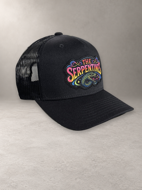 The Serpentines Neon Snake Trucker High, svart keps med färgstark patch på grå stenyta